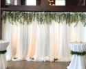 Florida and Carolina Garlands took this plain pipe and drape and turned it into something magical... If you would love this look to DIY just choose our collections and go to bunches and look for the Italian Ruscus decorations and order as many as you need and happy decorating!